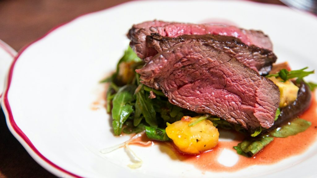 Sappige medium-rare biefstuk op rucola met geroosterde groenten en een rode wijnsaus