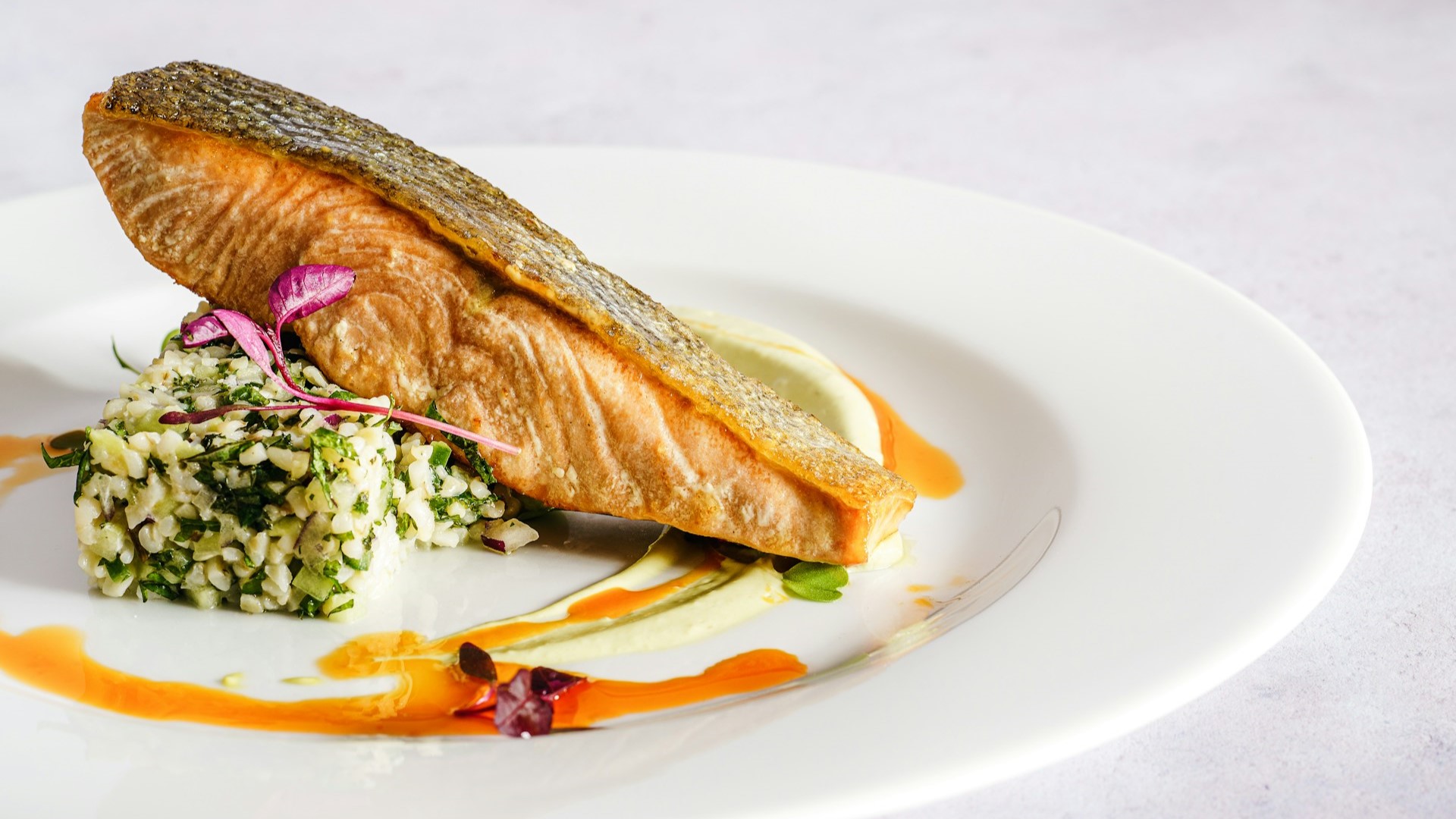 Goudbruin gebakken zalmfilet met krokante huid, geserveerd op een bedje van tabouleh en romige saus