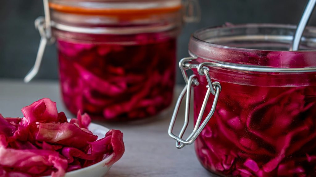 Gefermenteerde groenten bereiden met rode kool in glazen weckpotten, klaar om te serveren.