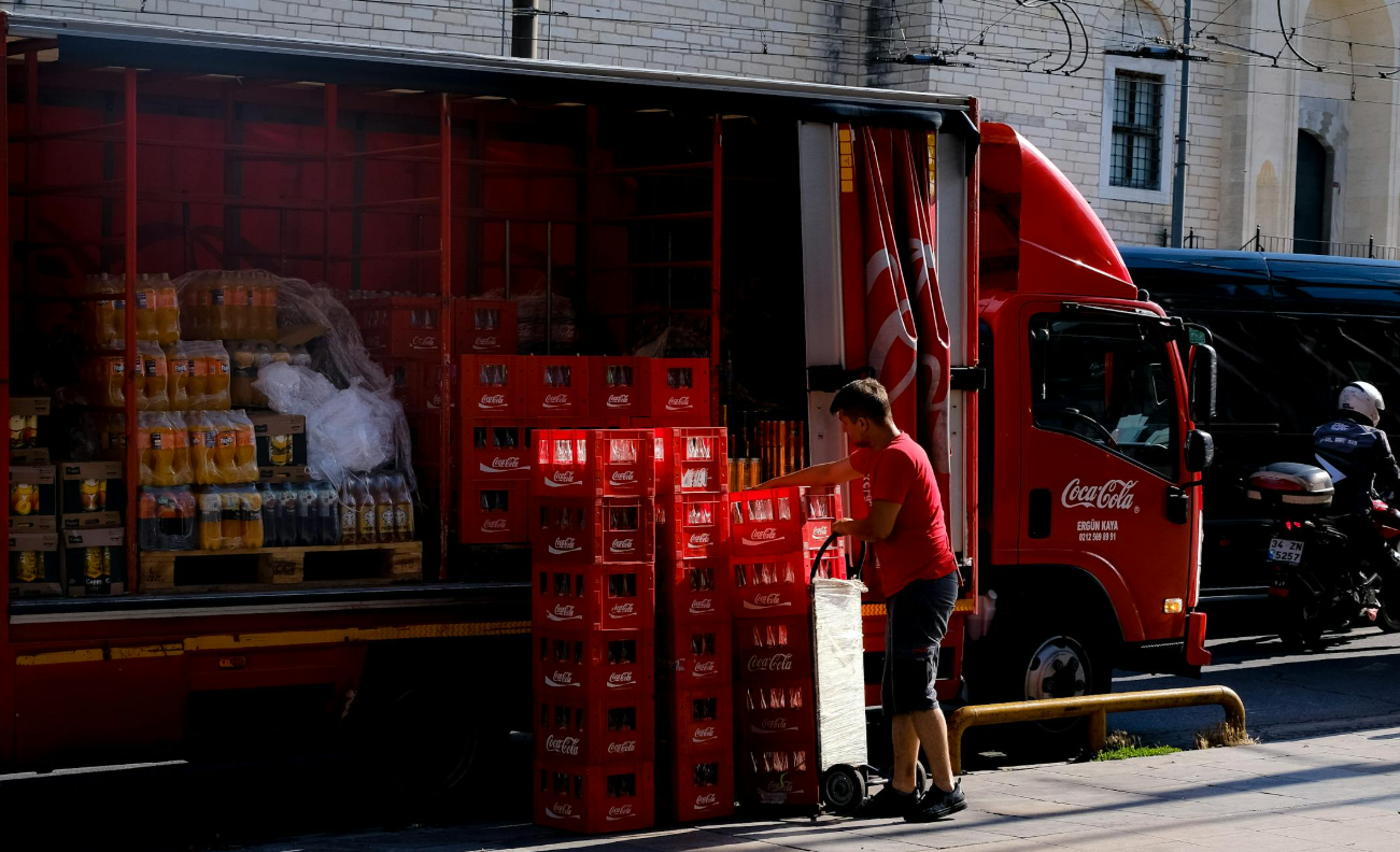 Chauffeur levert drankkratten af met steekwagen bij restaurant, voorbeeld van grote levering in horeca