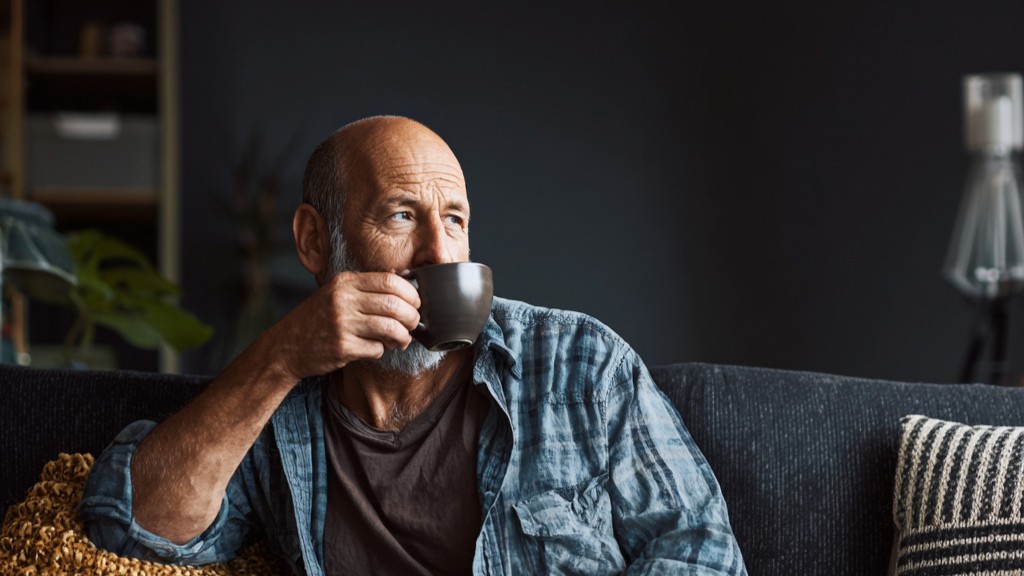 Man drinkt koffie op de bank in de woonkamer